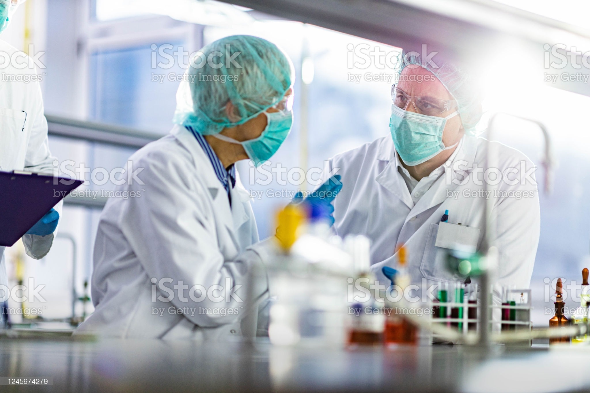 Two chemists communicating while working in laboratory. Focus is on man. Two chemists communicating while working in laboratory. Focus is on man.